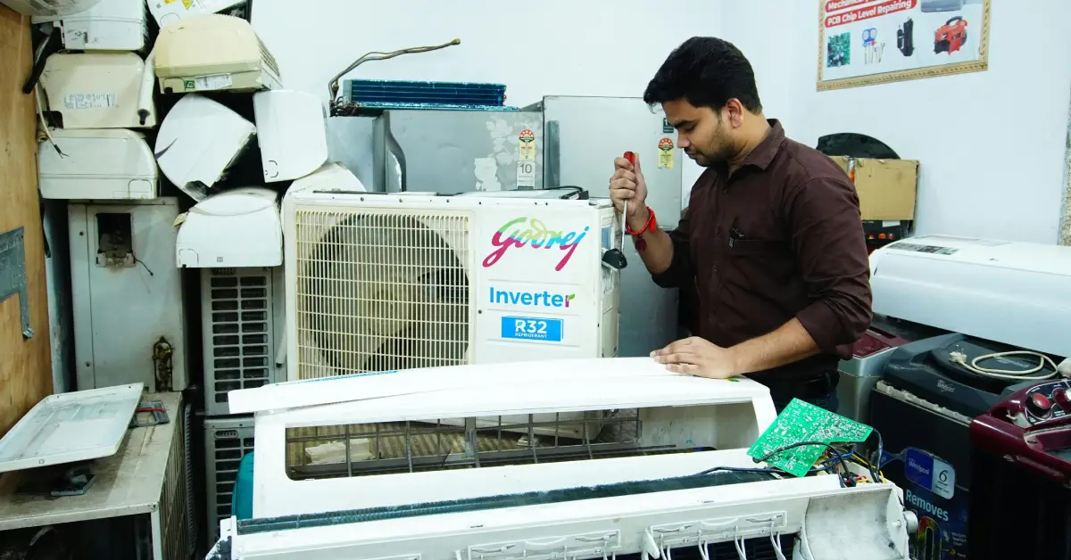 AC technician repairing split air conditioner indoor unit in Gurgaon with tools during maintenance service
